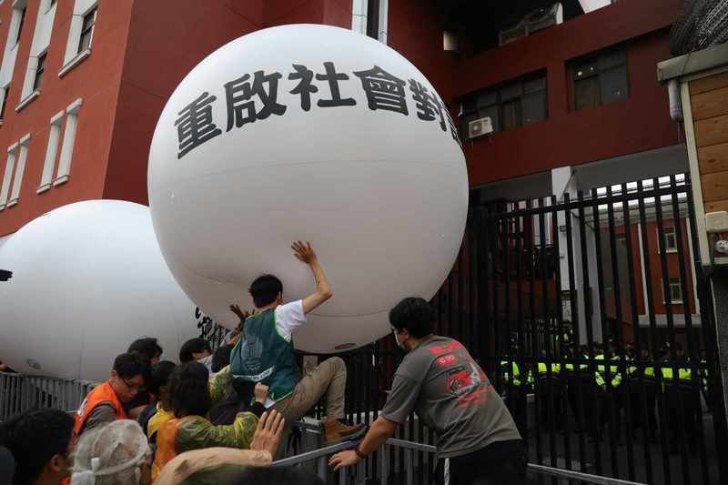 濟南路舞台推出兩顆巨大白球，寫著「公民捍衛民主」「重啟社會對話」兩句文字，由民眾群體推送，欲將訴求送入立法院。（攝影／鄭宇辰）
