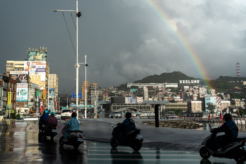 雨後的基隆海洋廣場邊，一道彩虹畫過基隆地標，伴隨正準備通勤、上工的在地人。（攝影／陳曉威）