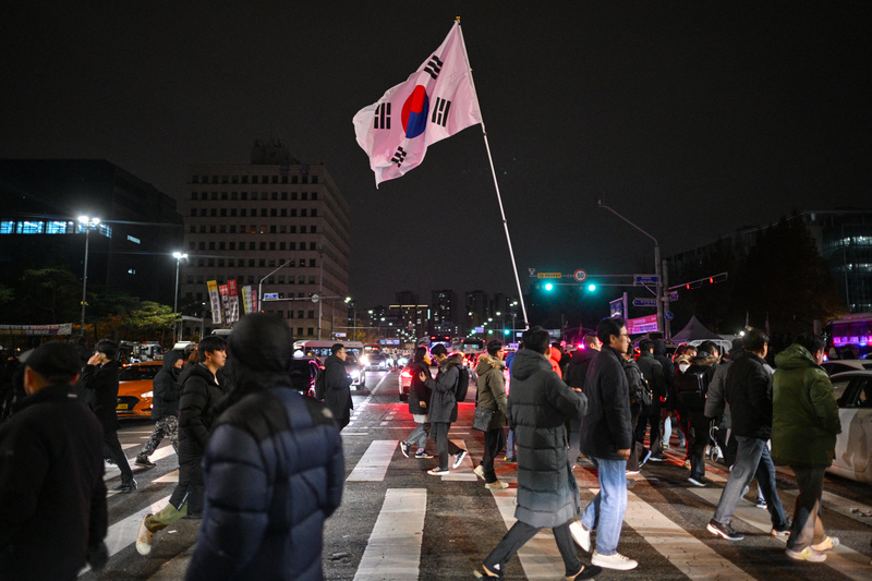 尹錫悅宣布緊急戒嚴令後，民眾在首爾國會大廈外高舉韓國國旗。（攝影／ANTHONY WALLACE／AFP）