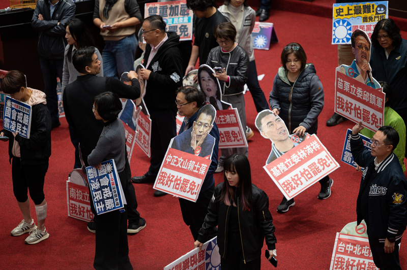 12月20日，民進黨立法委員在議場拿出抗議《選罷法》修法的手舉牌。（攝影／林彥廷）