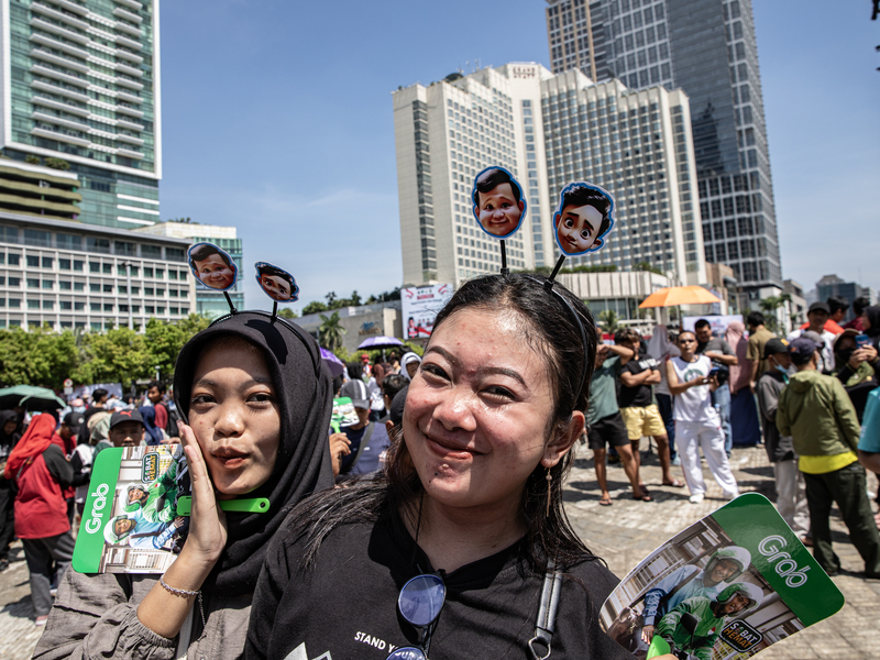 On October 20, 2024, Prabowo Subianto was sworn in as Indonesia's 8th president. Supporters lined the streets to await his parade convoy, with one displaying headgear featuring cartoon version figures of President Prabowo (left) and Vice President Gibran Rakabuming, the eldest son of former President Joko Widodo, from their election campaign. (Photo by Oscar Siagian/Getty Images)